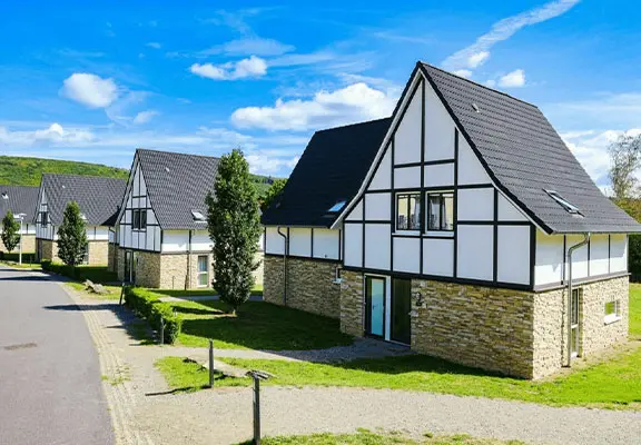 Groepsaccommodatie met meerdere vakantiehuizen op een rustig vakantiepark in groene heuvelachtige omgeving.