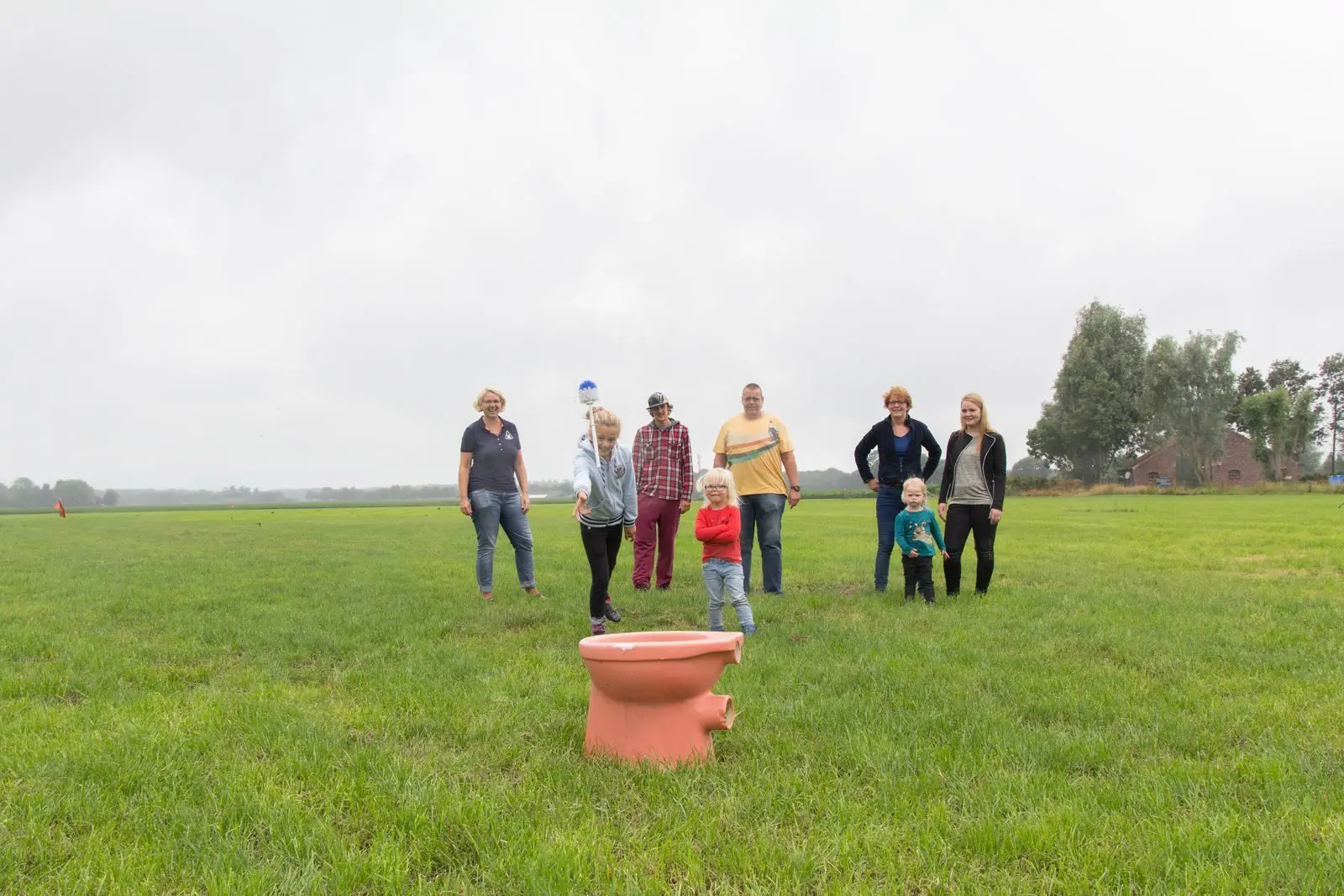 Groep mensen speelt buitenactiviteit op grasveld tijdens familieweekend.
